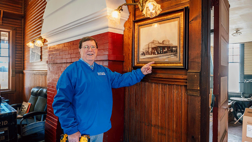 Paul Griffith points to old train depot picture
